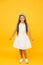 Cute girly girl. Happy girl yellow background. Fashion look of small girl. Little girl wear long brunette hair. Beauty