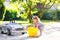 Cute gorgeous toddler girl washing big old toy car in summer garden, outdoors. Happy healthy little child cleaning car