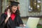 A cute graduate in academic gown having a vieo call and feeling happy