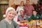 Cute grandmother in santa hat posing in front of her family