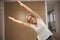 Cute grandmother is standing in a room in triangle pose