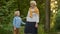 Cute grandson holding hands with his joyful elderly grandmother during walking at summer park.