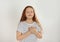 Cute grateful little girl with hands on chest against background