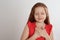 Cute grateful little girl with hands on chest against background