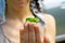 Cute green grasshopper sits on the fingers of a female hand on a summer sunny day, close up