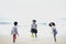 Cute groups of kids having fun together on sandy summer beach with blue sea, happy childhood friends playing ball on tropical