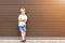 Cute grumpy blond child in casual clothing standing against brown garage door. Angry kid boy with crossed arms near house.Awkward