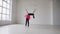 Cute gymnast doing circle with mace on the legs in the white studio on window background. Gymnastics girl dressed black