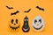 Cute Halloween pumpkins with funny smiling faces and paper bats flying over orange background. Halloween.