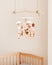 Cute handmade felt mobile on the crib for children. Brown and white colors. Bear, owl, deer, sheep, hedgehog and stars