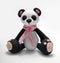 Cute handmade toy. knitted little animal. panda with a scarf around his neck. on a gray background