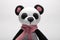 Cute handmade toy. knitted little animal. panda with a scarf on the neck. on a gray background. close-up