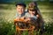 Cute handsome boy wearing jeans and shirt sittingand playing on wooden chair together with beautifull girl on meadow of chamomiles