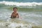Cute happy baby boy bathes in the sea with waves, vacations.