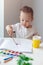 Cute happy baby boy painting with colorful paints at home