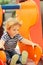 Cute happy baby boy riding from orange slide board