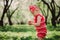 Cute happy baby girl in funny pink romper walking outdoor in spring garden