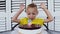 Cute happy boy celebrating its fifth birthday, in front of him delicious cake with candle in the form of `5`. Happy