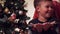 Cute happy boy holds artificial snow in his hand and blows them into the camera.