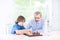 Cute happy boy playing chess with his grandfather