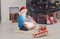 Cute happy boy in santa hat unwrapping christmas presents