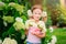 Cute happy child girl with hydrangea flowers bouquet in summer garden