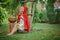 Cute happy child girl playing little red riding hood in summer garden