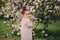 Cute happy dreamy toddler child girl walking in blooming spring garden, celebrating easter outdoor