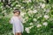 Cute happy dreamy toddler child girl walking in blooming spring garden, celebrating easter outdoor