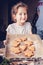 Cute happy girl hold a baking sheet with delicious gingerbread cookies. Homemade sweet Christmas pastries. Vertical shot