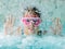 Cute happy girl in pink goggles mask in the swimming pool