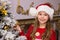 Cute happy girl in red hat hangs decorations