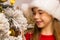 Cute happy girl in red hat hangs decorations