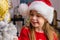 Cute happy girl in red hat hangs decorations