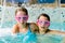 Cute happy girls in pink goggles mask in the swimming pool