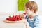 Cute happy kid eating tasty ripe strawberries on the kitchen