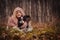 Cute happy kid girl with her dog on cozy autumn walk in forest