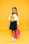 cute and happy kid holding books and backpack on orange .