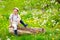 Cute happy kid sitting on wooden stump in spring garden