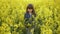 Cute happy little girl 6-8 years old walking in the summer in a yellow canola field