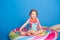 cute happy little girl in swimming suit smiling sitting on colorful inflatable mattress on blue background.