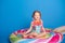 cute happy little girl in swimming suit smiling sitting on colorful inflatable mattress on blue background.