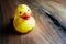 Cute and happy plastic yellow duck on a wooden surface