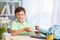 Cute happy schoolboy puts office supplies in a backpack. Preparation for school