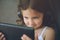 Cute happy smiling small caucasian girl in headphones looking on tablet device screen hearing music tune