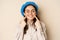 Cute happy woman smiling white teeth, pointing at her dimples, standing over beige background