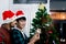 Cute happy young LGBT couple holding ball ornament to decorate Christmas tree, gay male lover sharing sweet special moment on