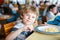 Cute healthy preschool boy eats pasta sitting in school canteen