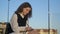 Cute high school girl in uniform writes something in a notebook. She sits alone in the school yard.