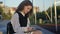 Cute high school girl in uniform writes something in a notebook. She sits alone in the school yard.